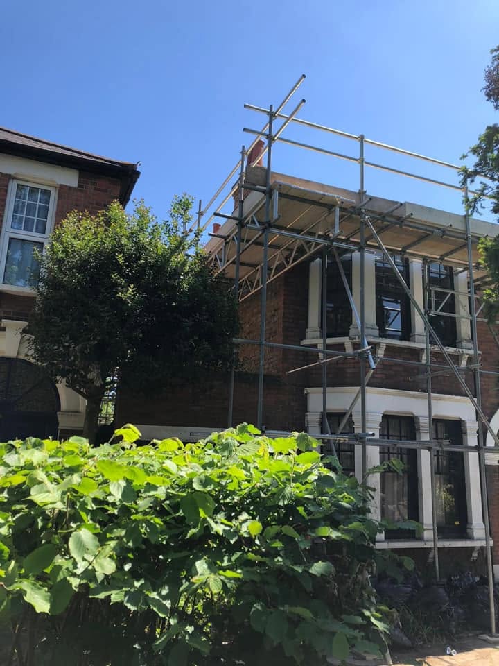 Scaffolded Victorian villa mid-refurbishment on a clear summer day